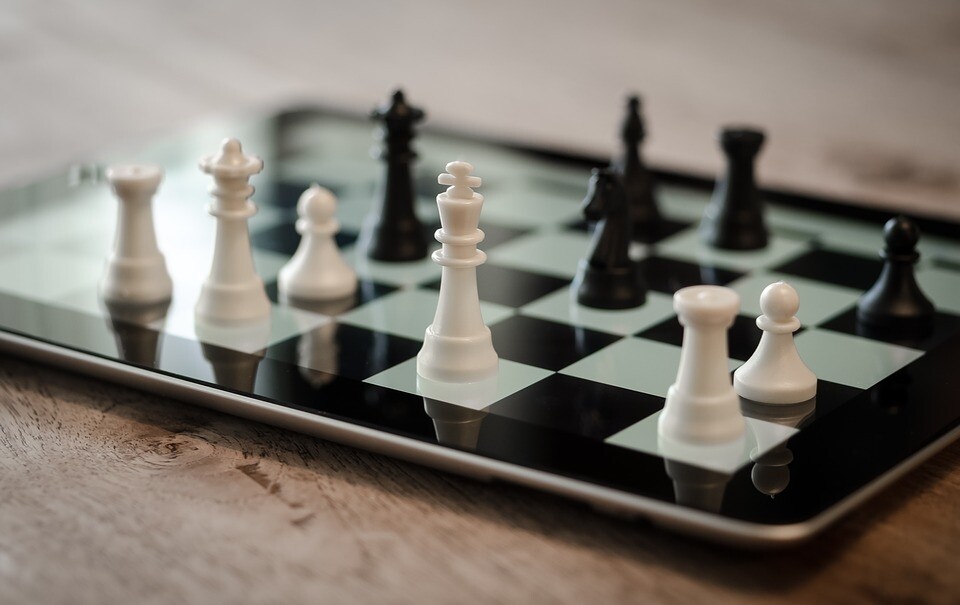 Chess pieces resting on electronic chessboard on tablet